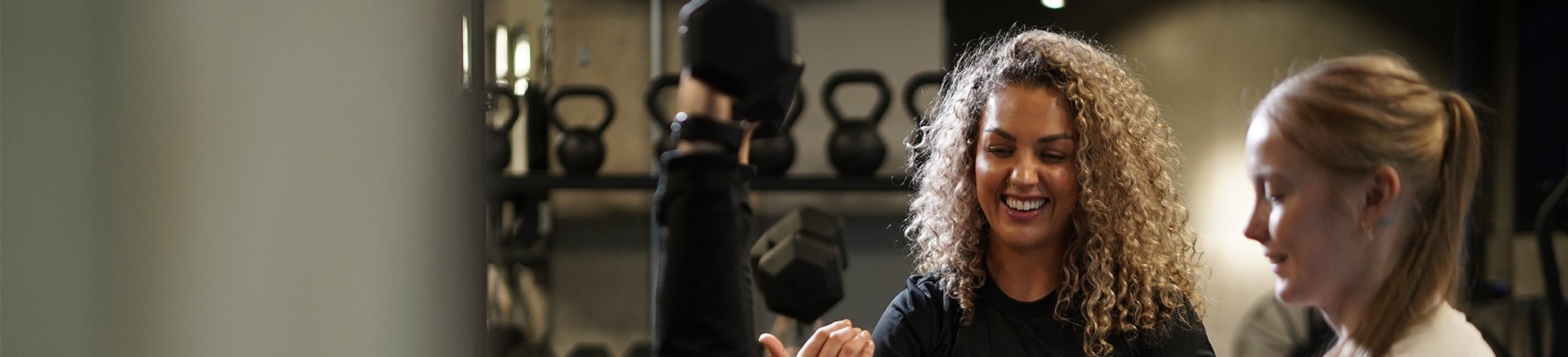 PT assisting 2 clients with a dumbbell chest press.